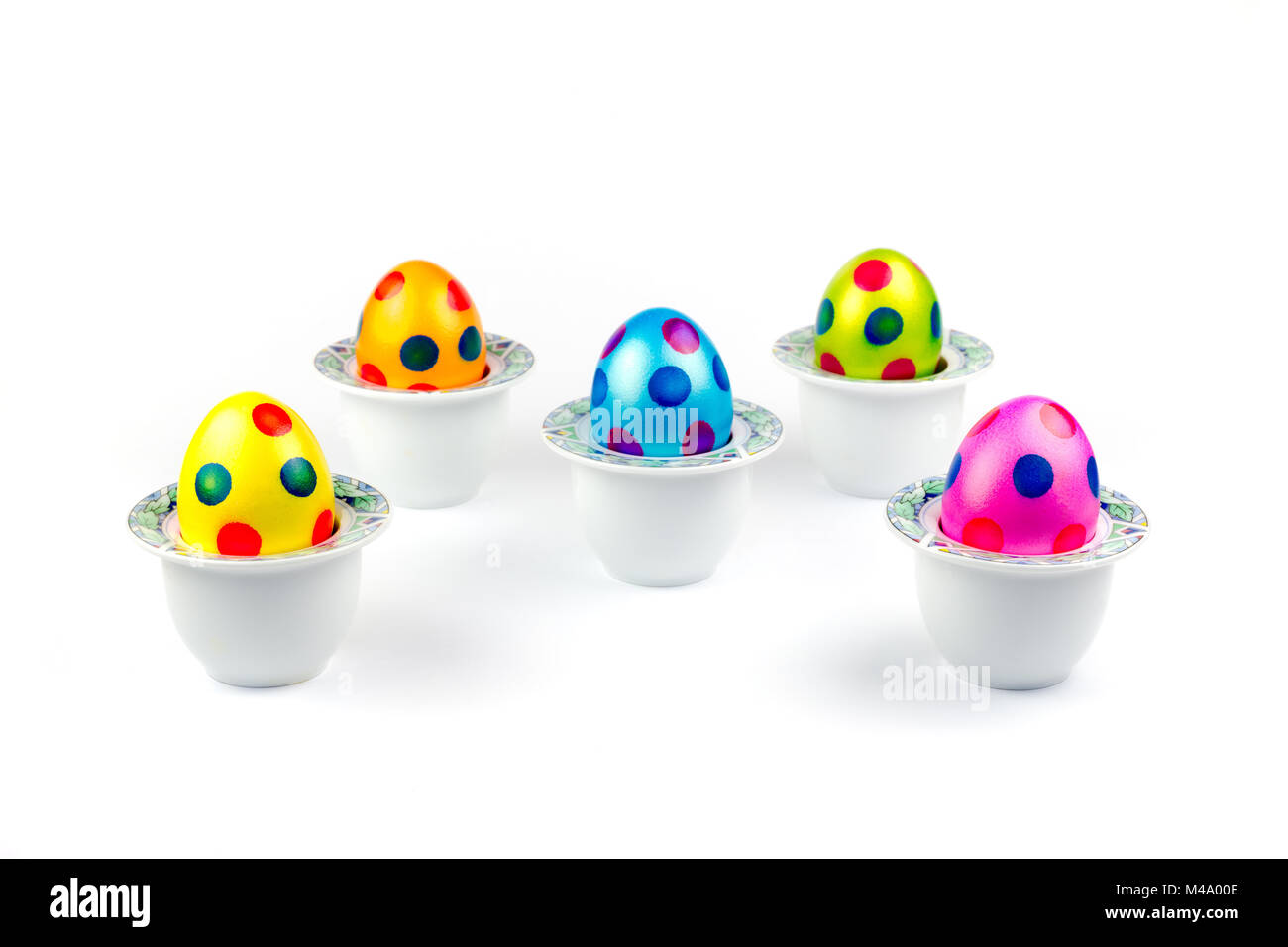 Painted easter eggs standing in porcelain egg cups on white Stock Photo