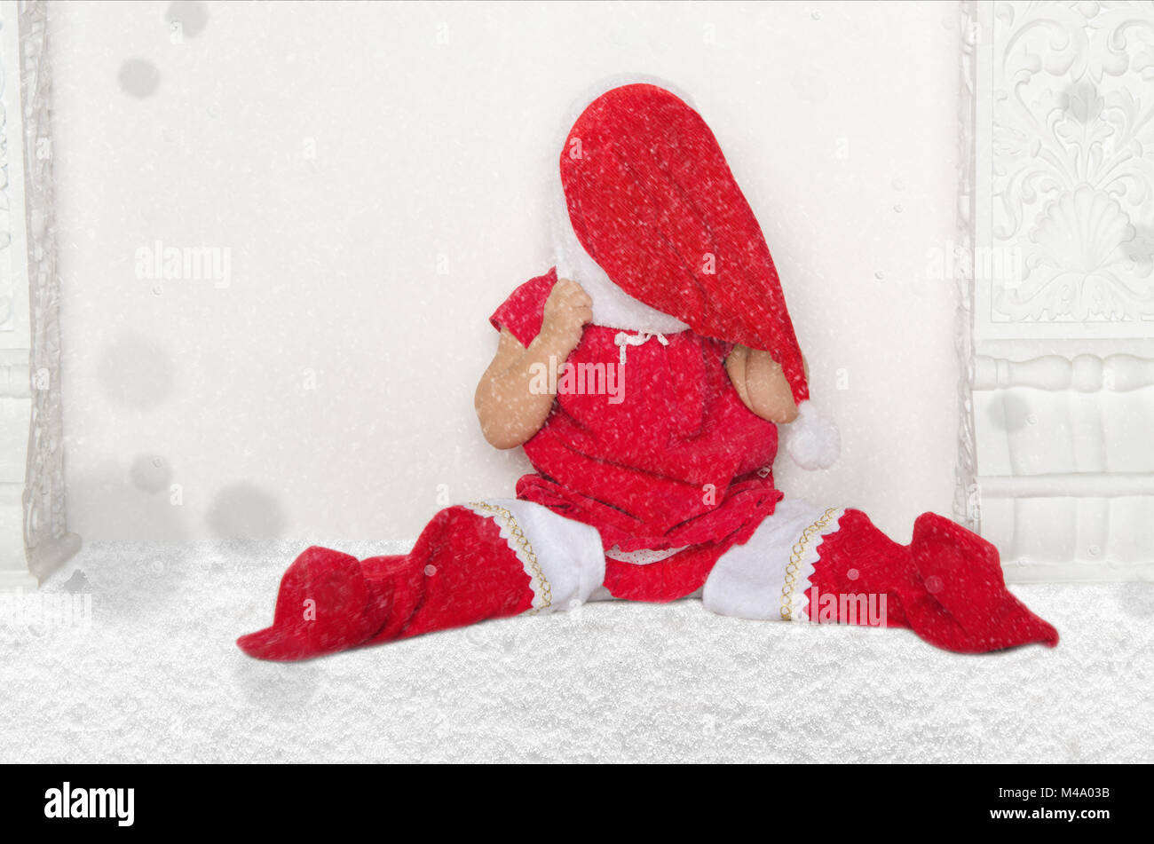 Small girl in Santa suit sitting on floor with snow Stock Photo