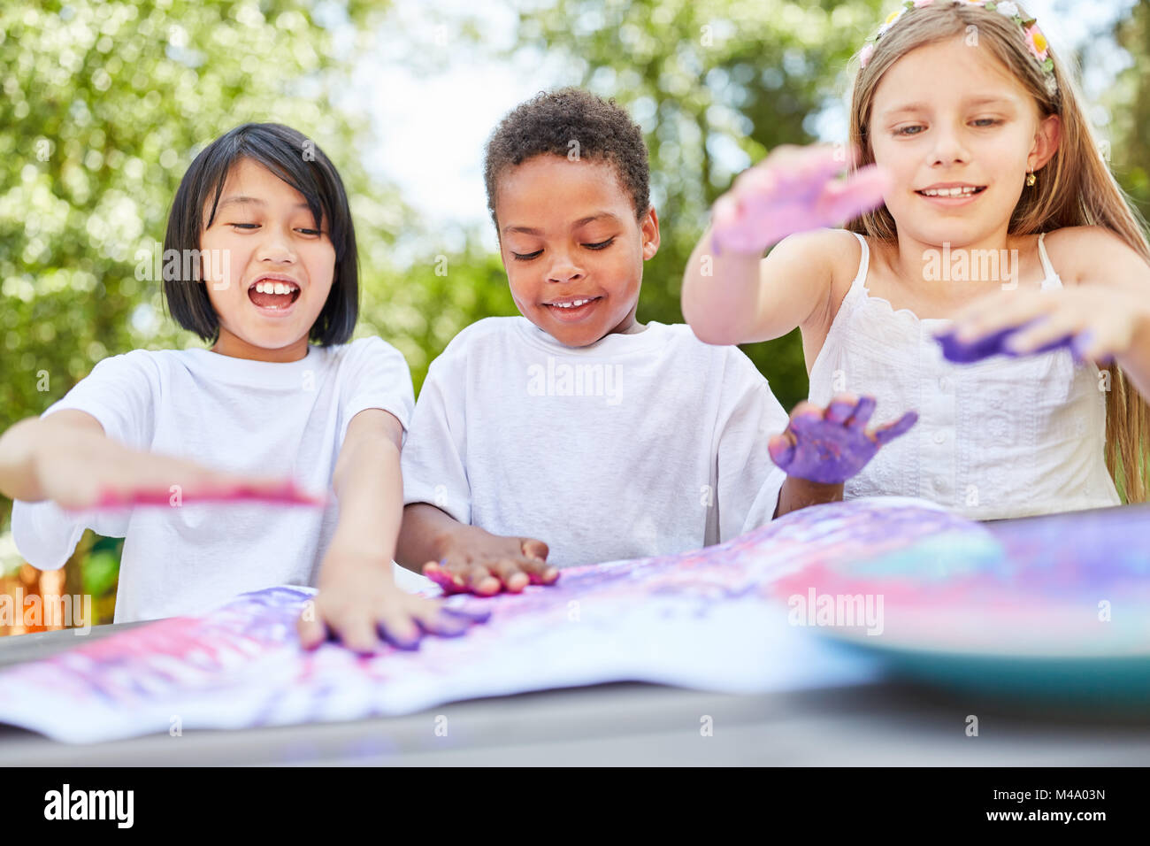 Creative kids as friends play with finger paints on kids birthday Stock Photo