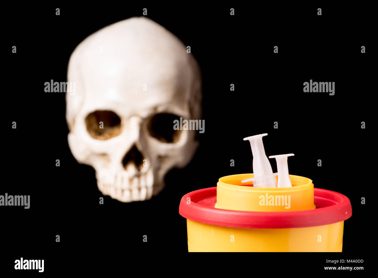 Medical waste container with syring and skull isolated on black background Stock Photo
