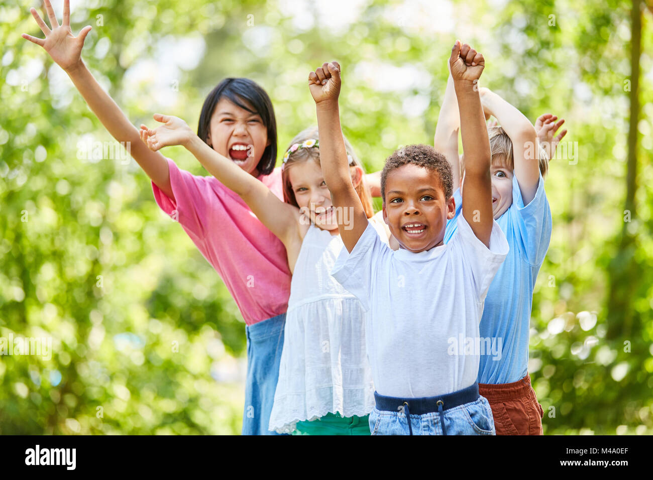 Multicultural group of children enthusiastically cheers on a children's birthday party Stock Photo