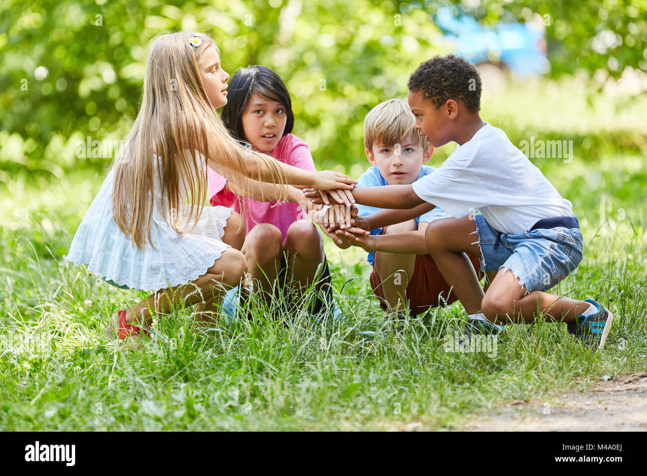 Multicultural group of children is stacking hands as a sign of friendship Stock Photo