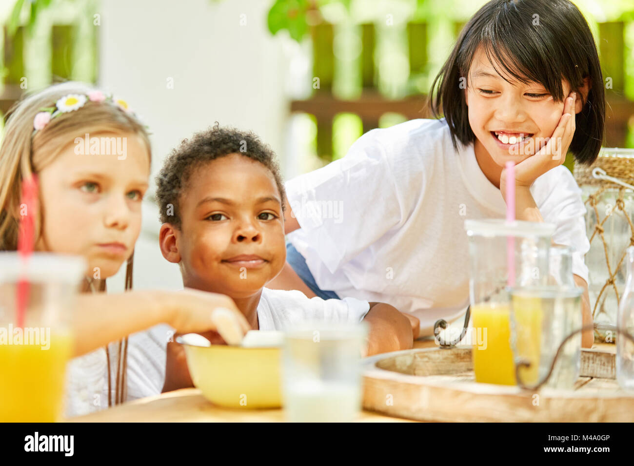 Multicultural group of children has breakfast together in kindergarten ...