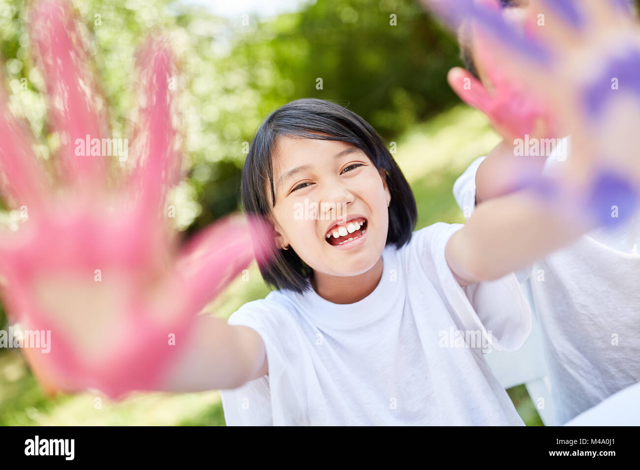 Asian girl is having fun while painting with finger paint in preschool Stock Photo