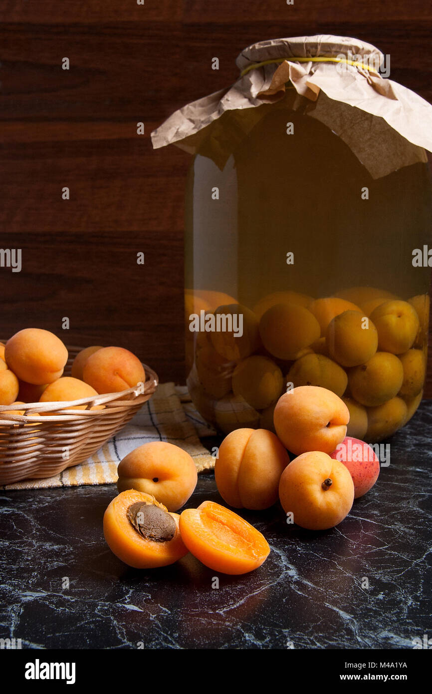 Ripe organic apricots harvested at summer time and big glass jar with