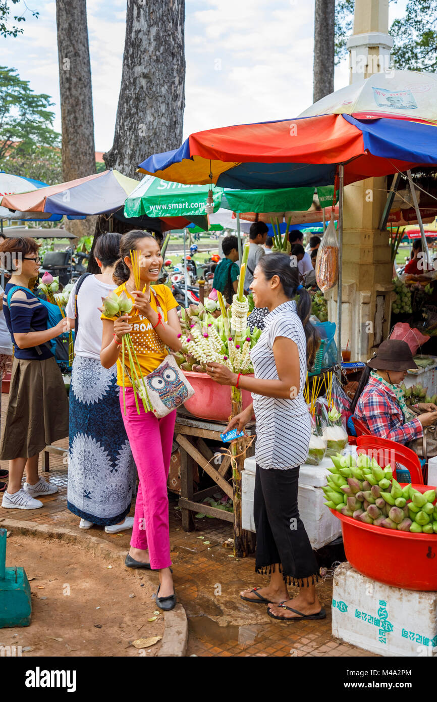 Happy local young women buying and selling votive offerings at a market stall at Ya Tep Shrine, Independence Gardens, Siem Reap, Cambodia Stock Photo