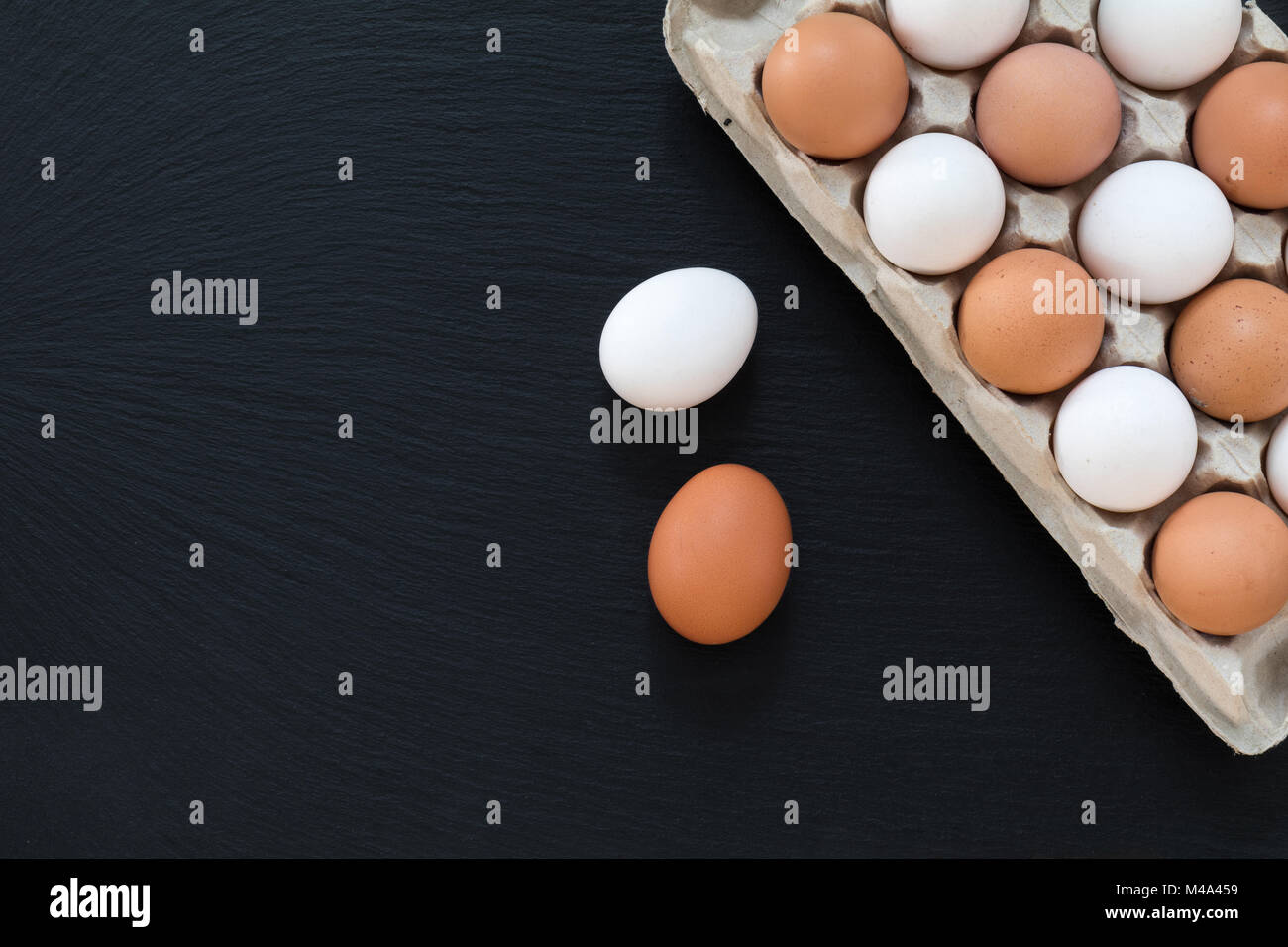 White and brown chicken eggs on black background Stock Photo - Alamy