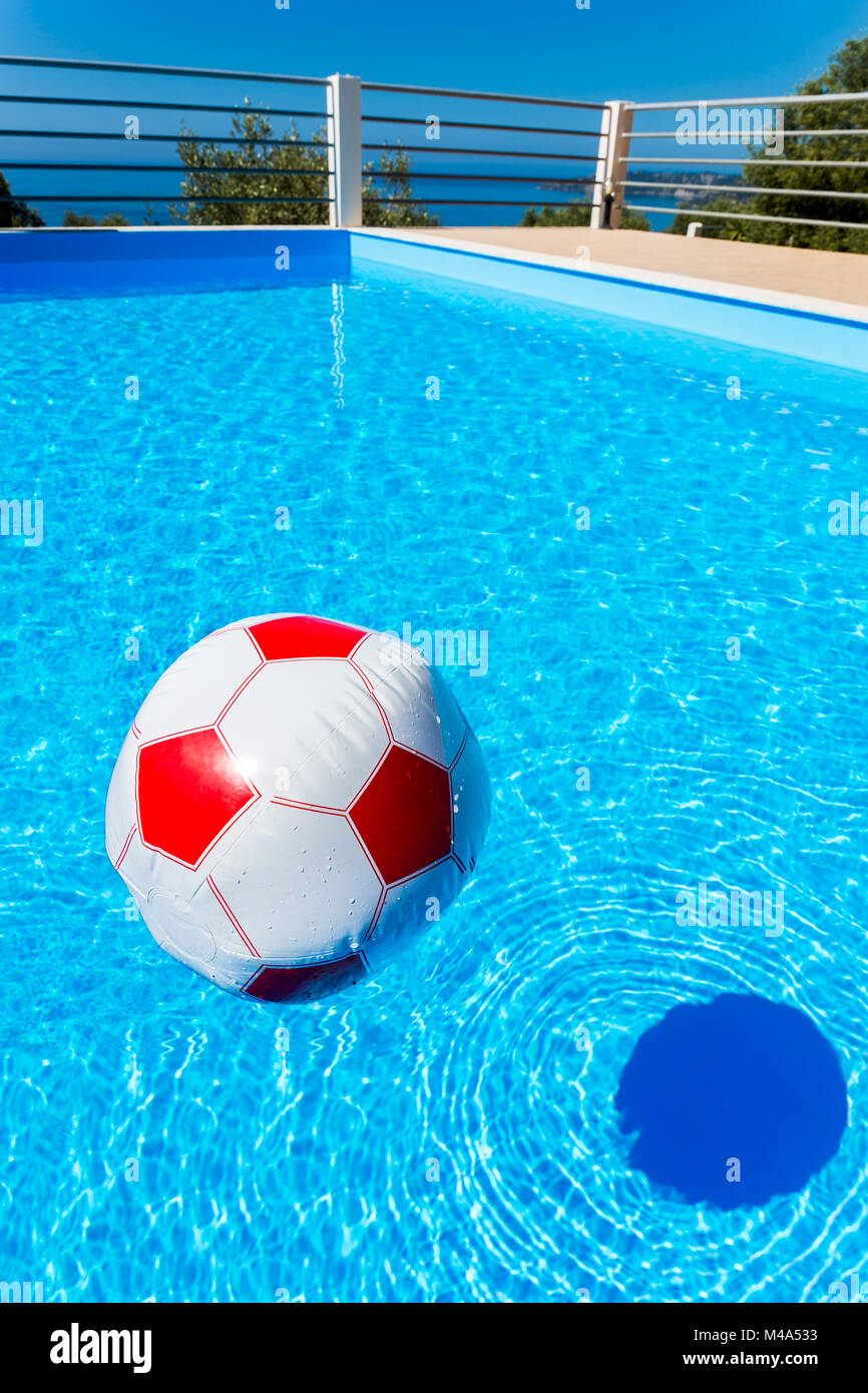 Beach ball floating on water in swimming pool Stock Photo