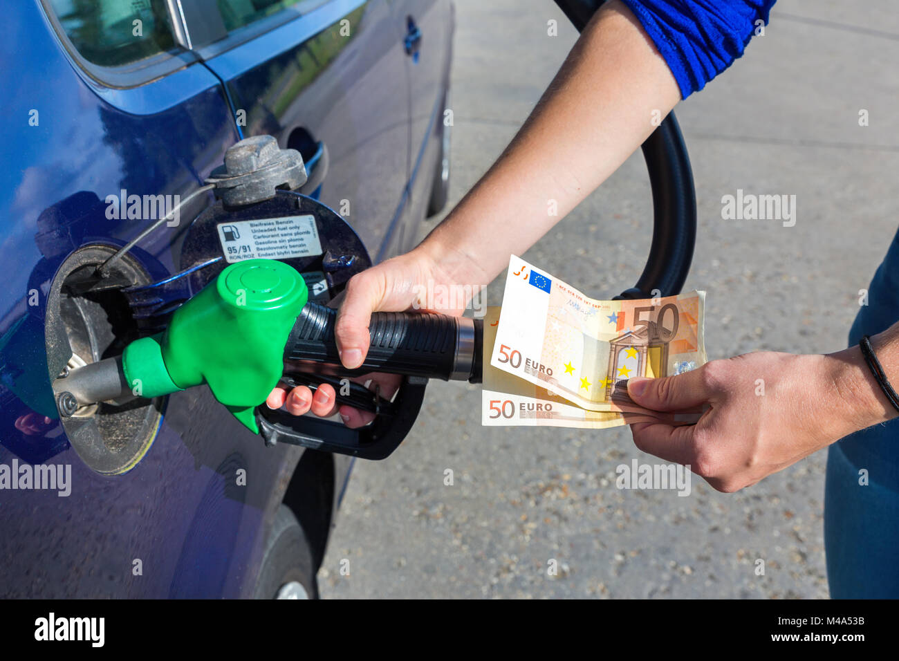 Woman fueling car tank and holding euro money Stock Photo