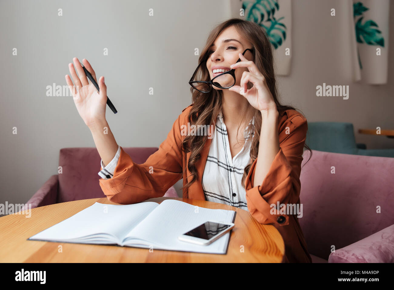 Portrait of a confident woman taking notes in a notepad while sitting ...