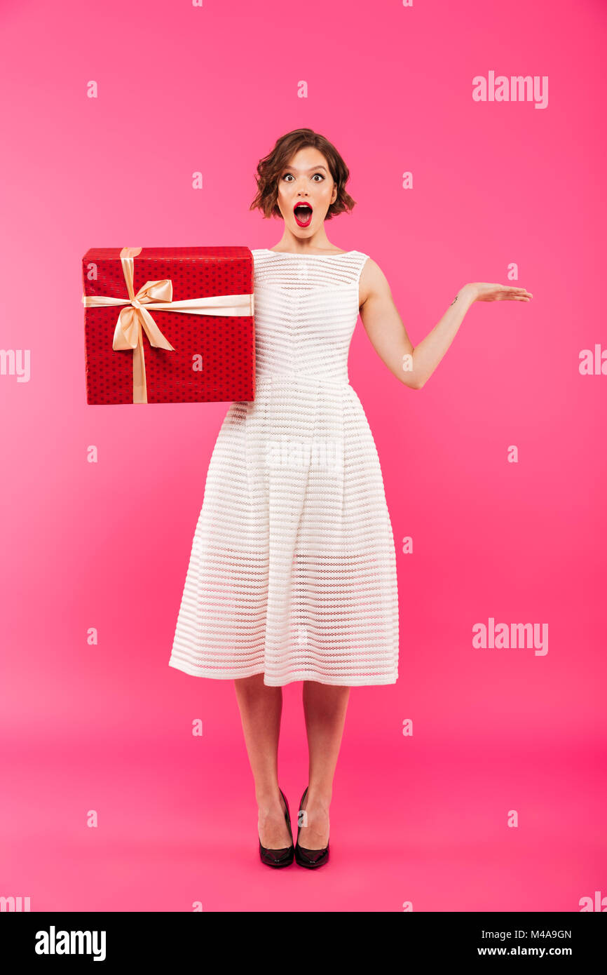 Full length portrait of a happy girl dressed in dress holding gift box ...
