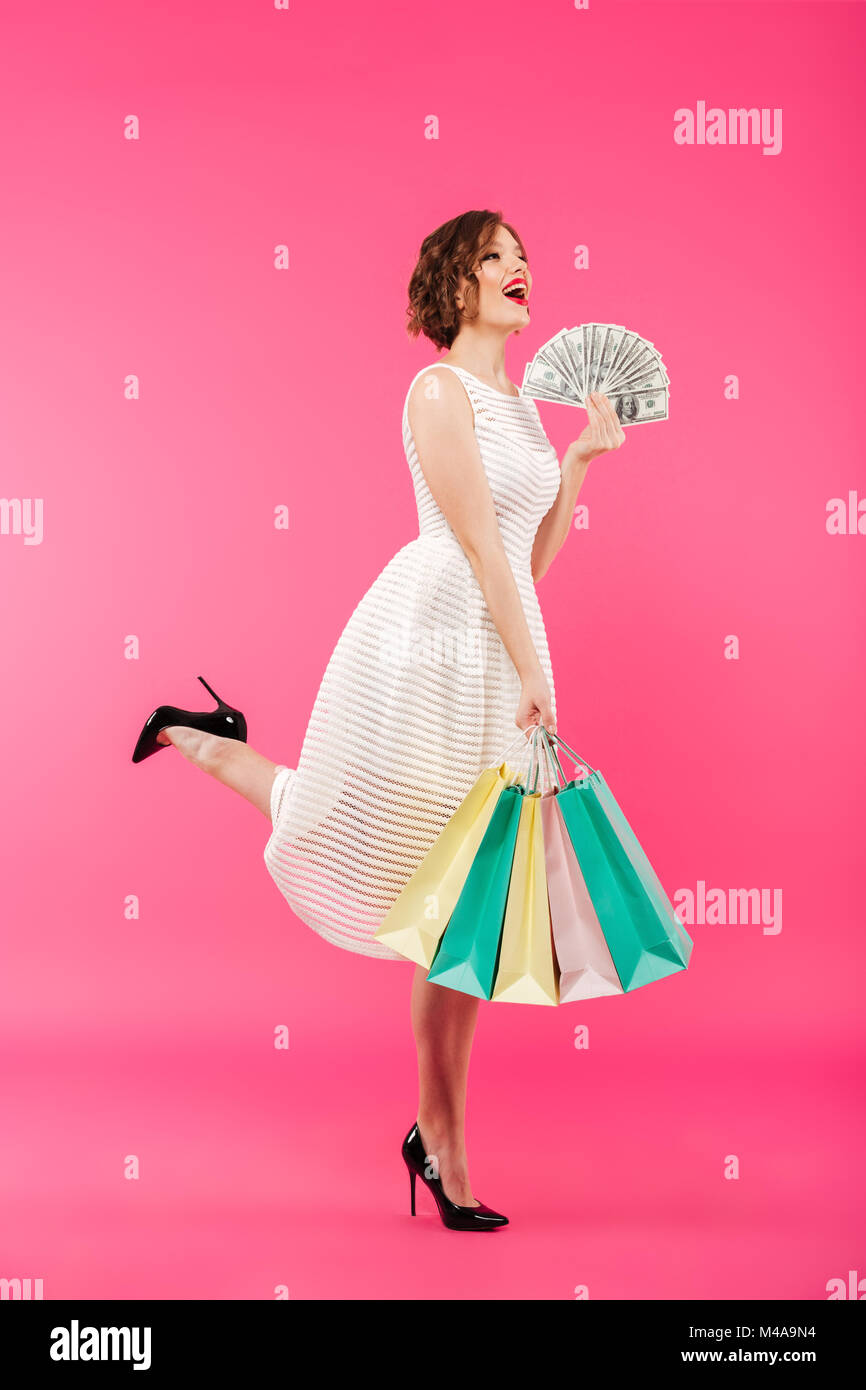 Full length portrait of a cheerful girl dressed in dress holding ...