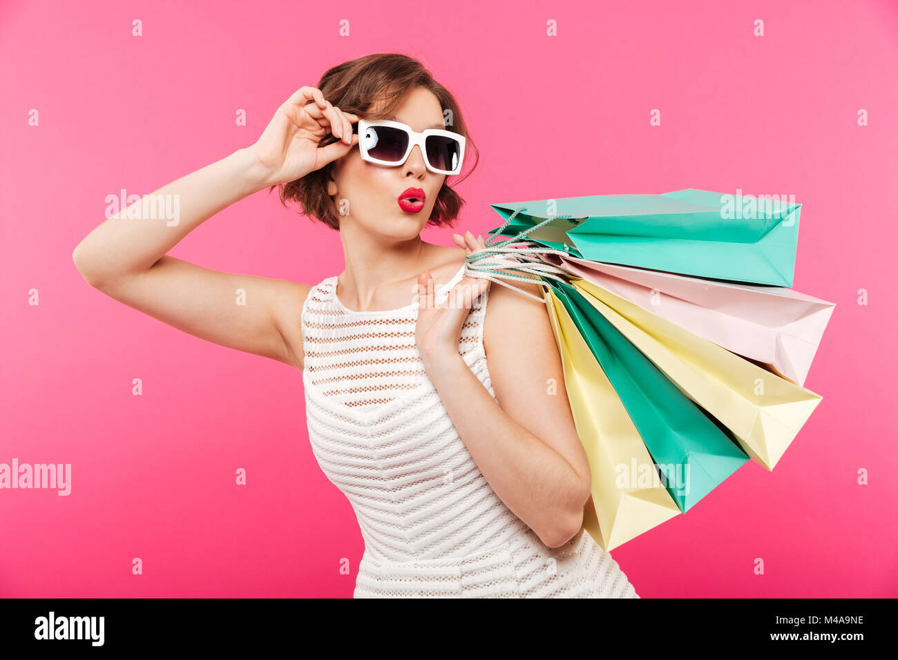 Portrait of a pretty girl dressed in dress holding shopping bags and ...