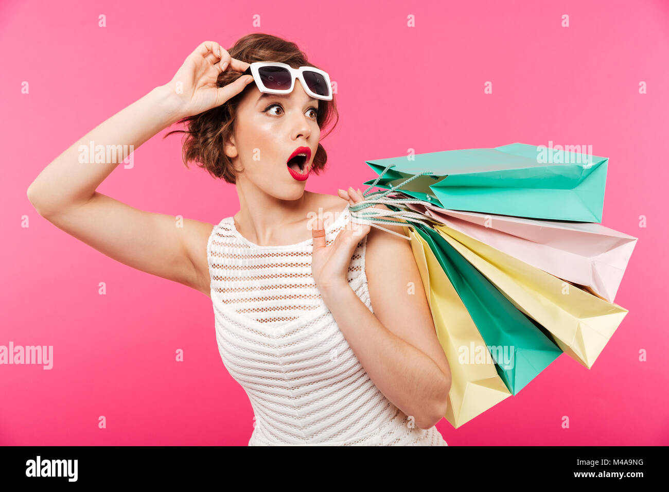 Portrait of a shocked girl dressed in dress holding shopping bags and ...