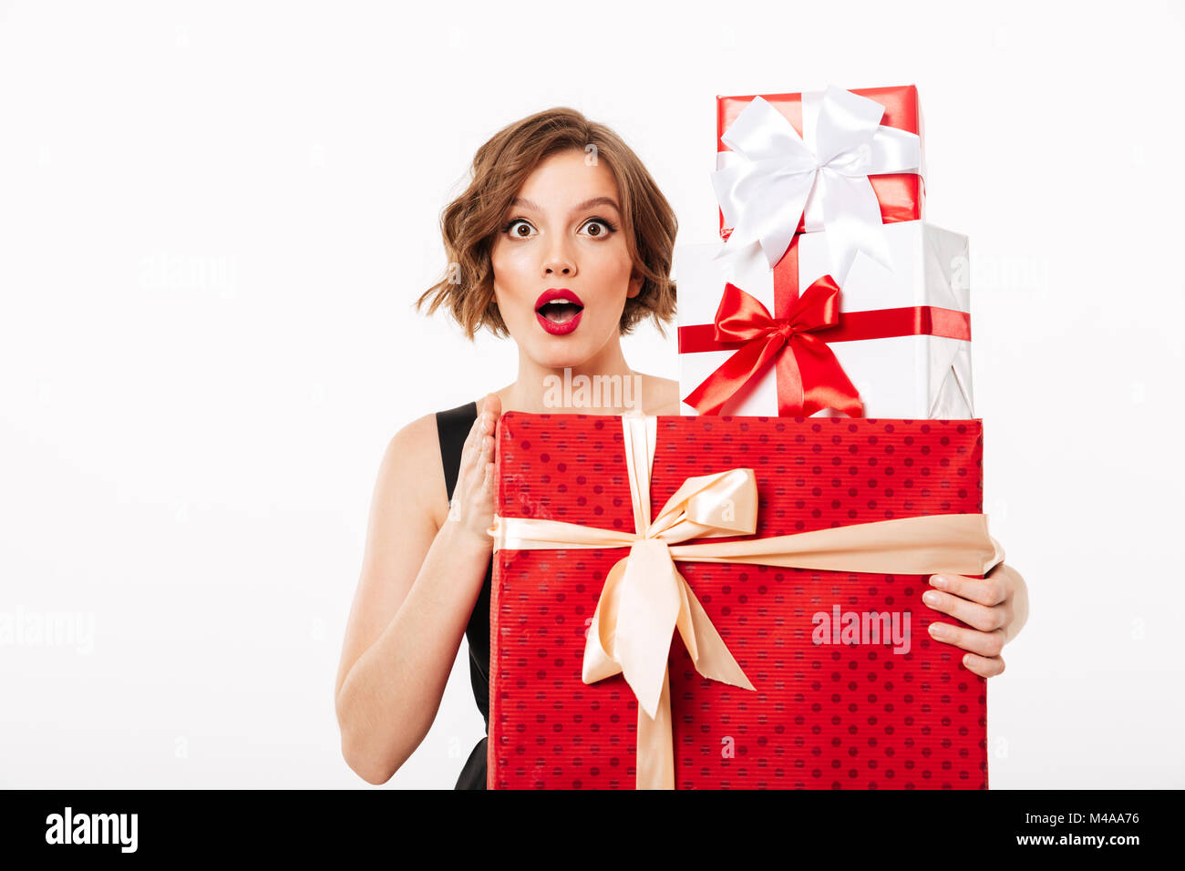 Portrait of a surprised girl dressed in black dress holding stack of ...