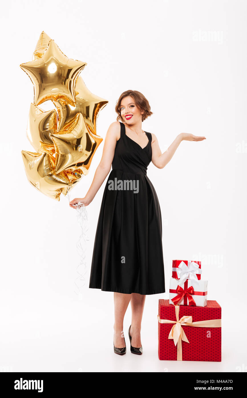 Full length portrait of a smiling girl dressed in black dress holding ...