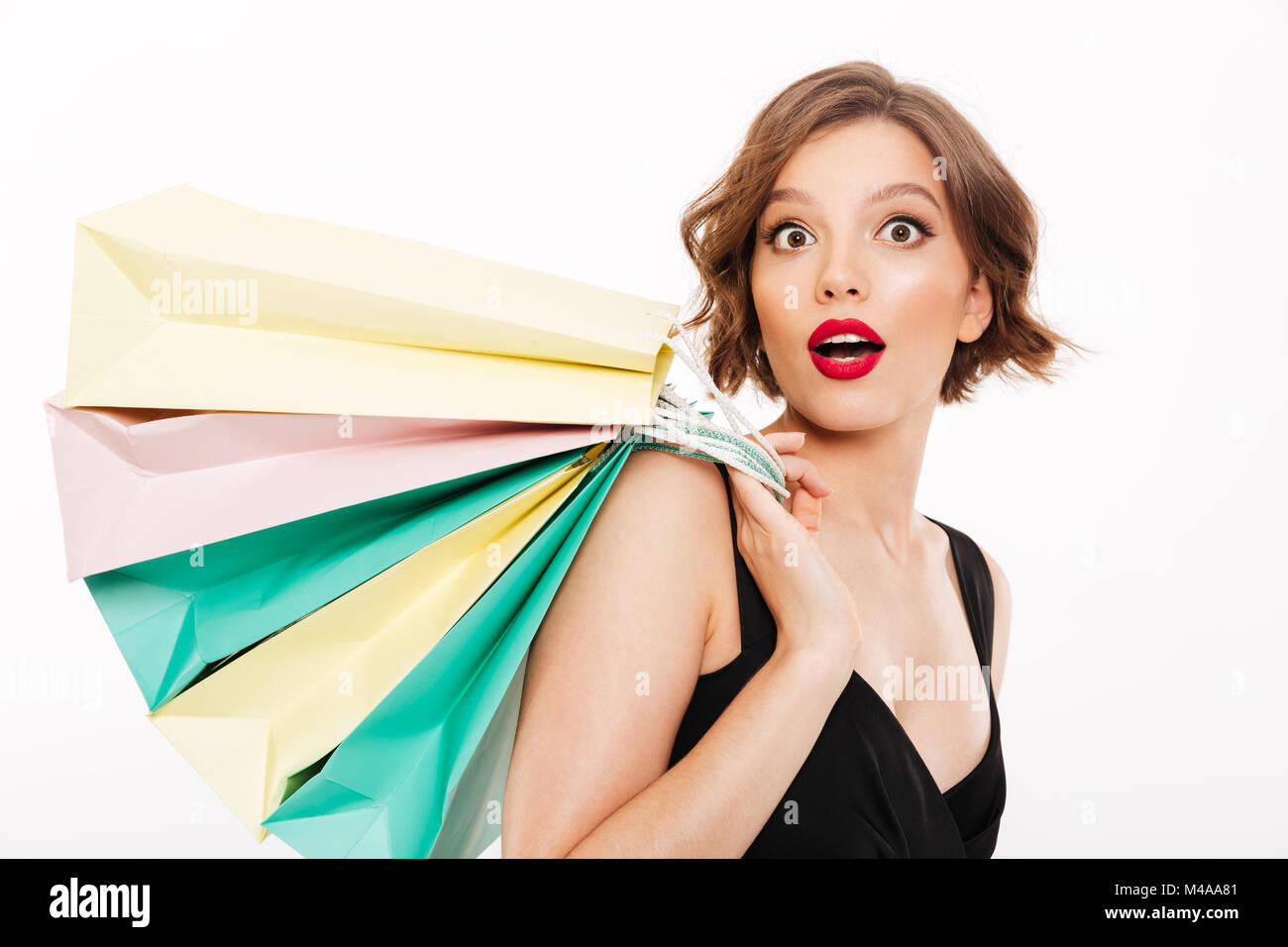 Portrait of a surprised girl dressed in black dress holding shopping ...