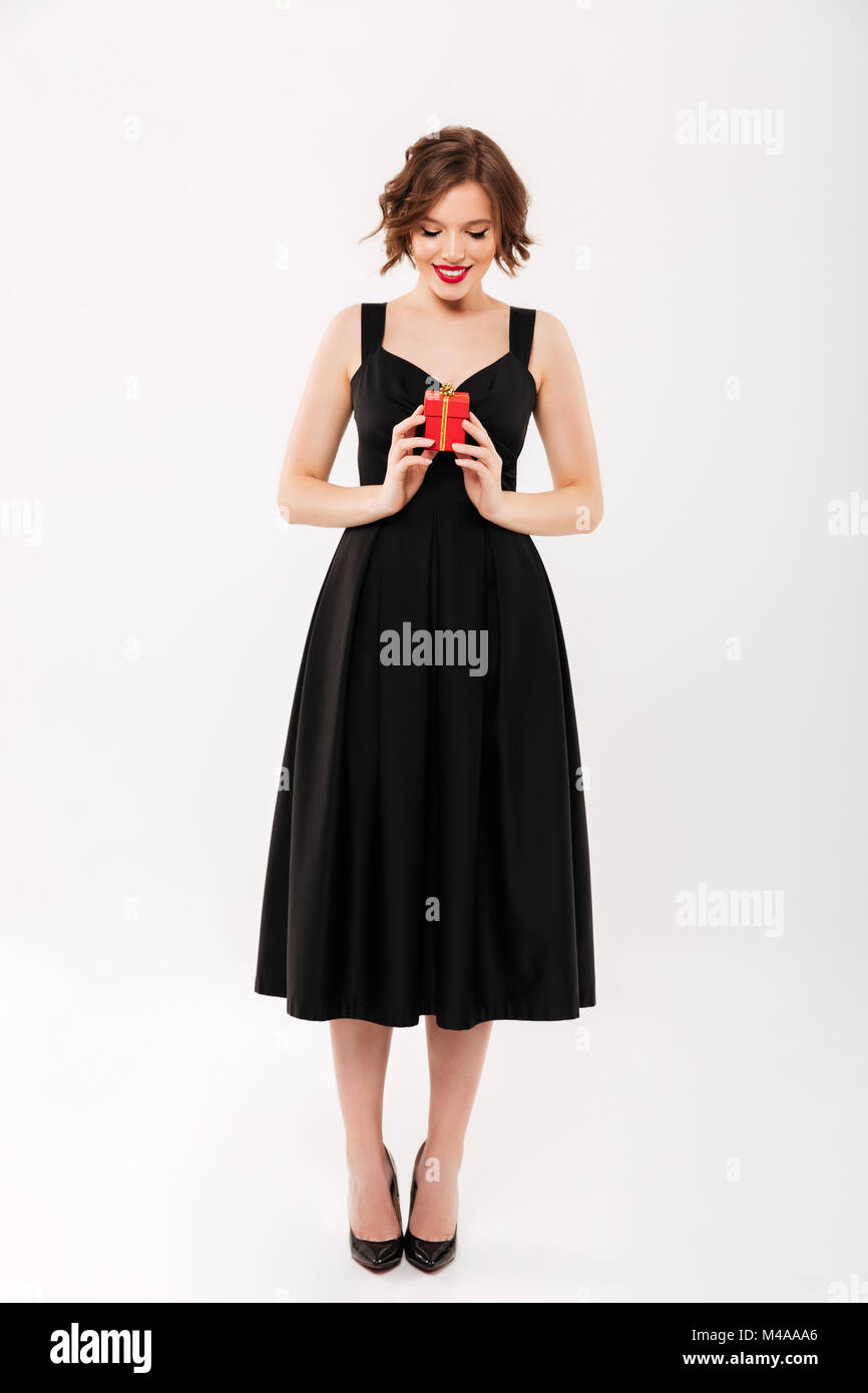 Full length portrait of a smiling girl dressed in black dress holding ...