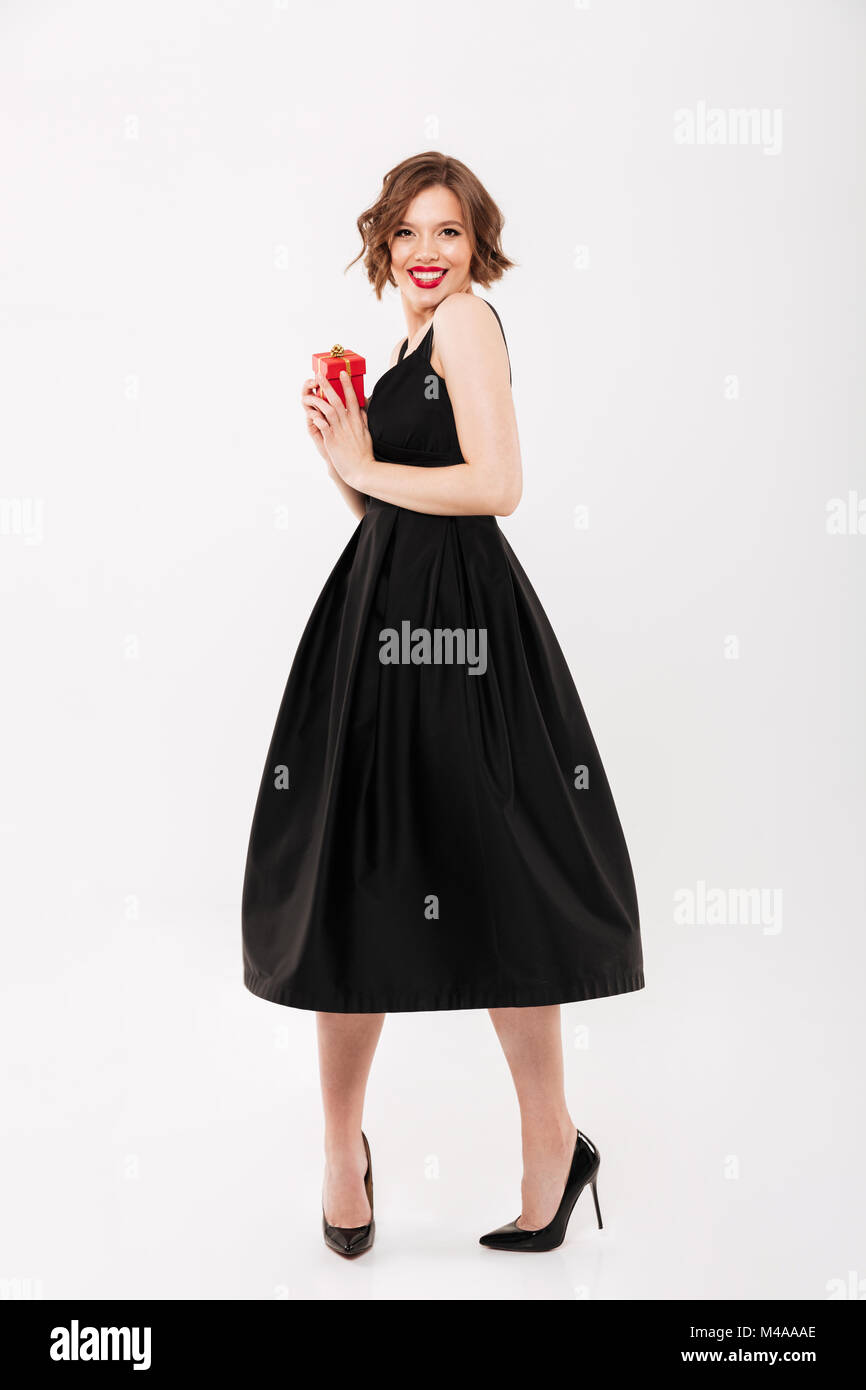 Full length portrait of a happy girl dressed in black dress holding ...