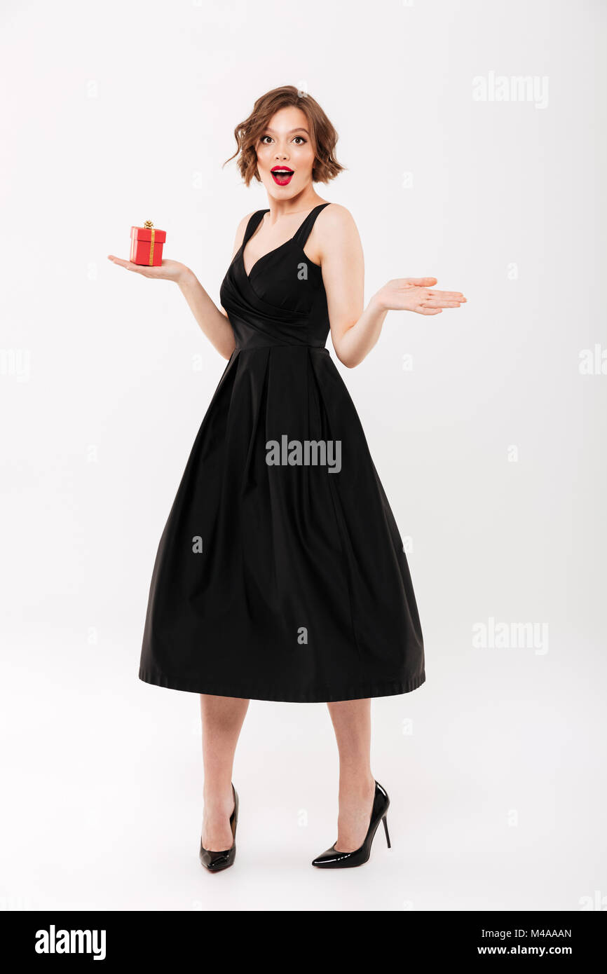Full length portrait of a joyful girl dressed in black dress holding ...