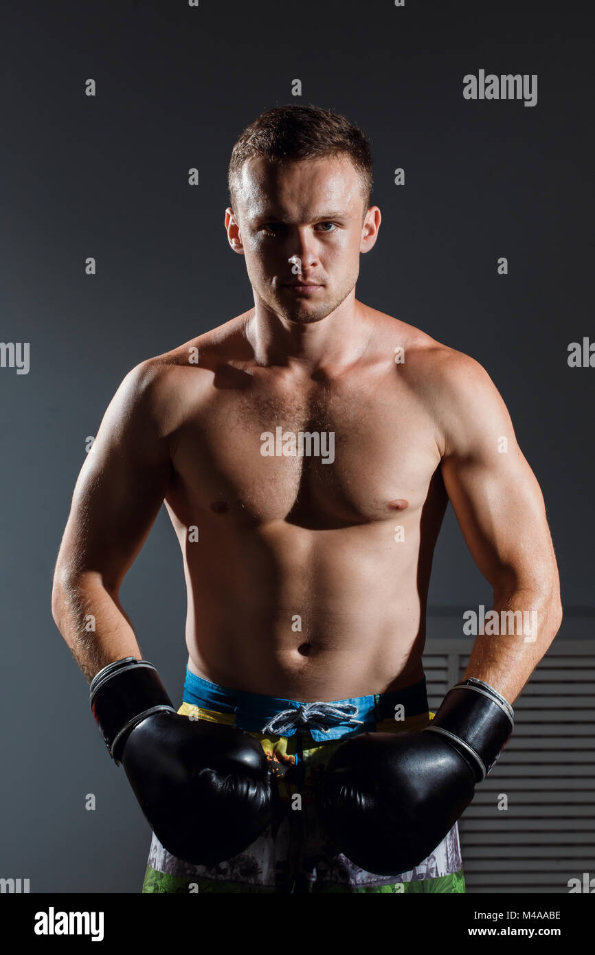Young handsome man or healthy boxer or Thai boxer with six pack wearing boxing gloves Stock Photo