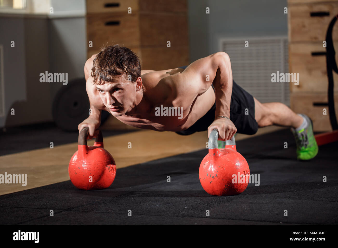 Gym man push-up strength pushup exercise with Kettlebell in a workout Stock Photo