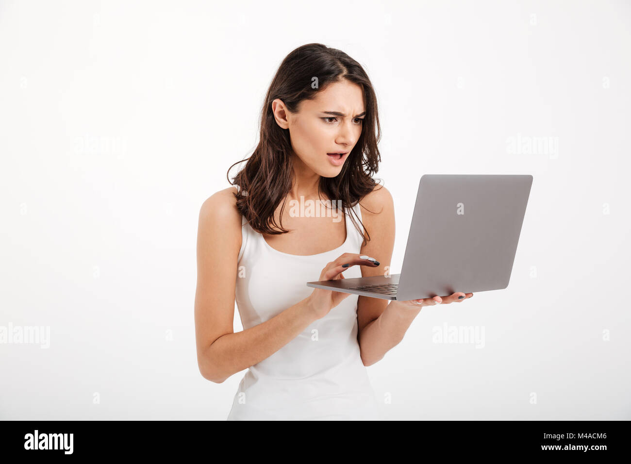 Portrait of a confused girl dressed in tank-top using laptop computer ...