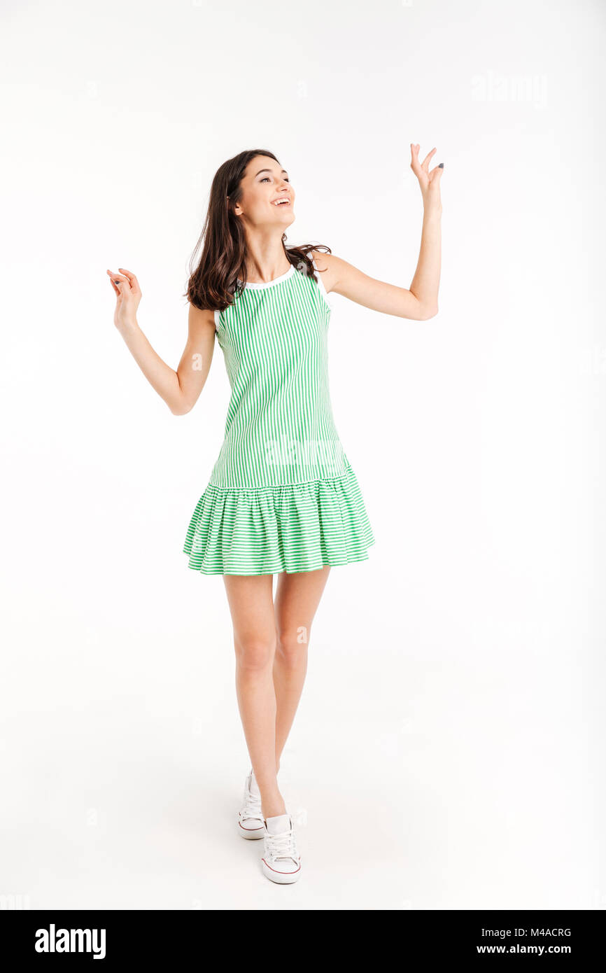 Full length portrait of a cheerful girl dressed in dress posing while ...
