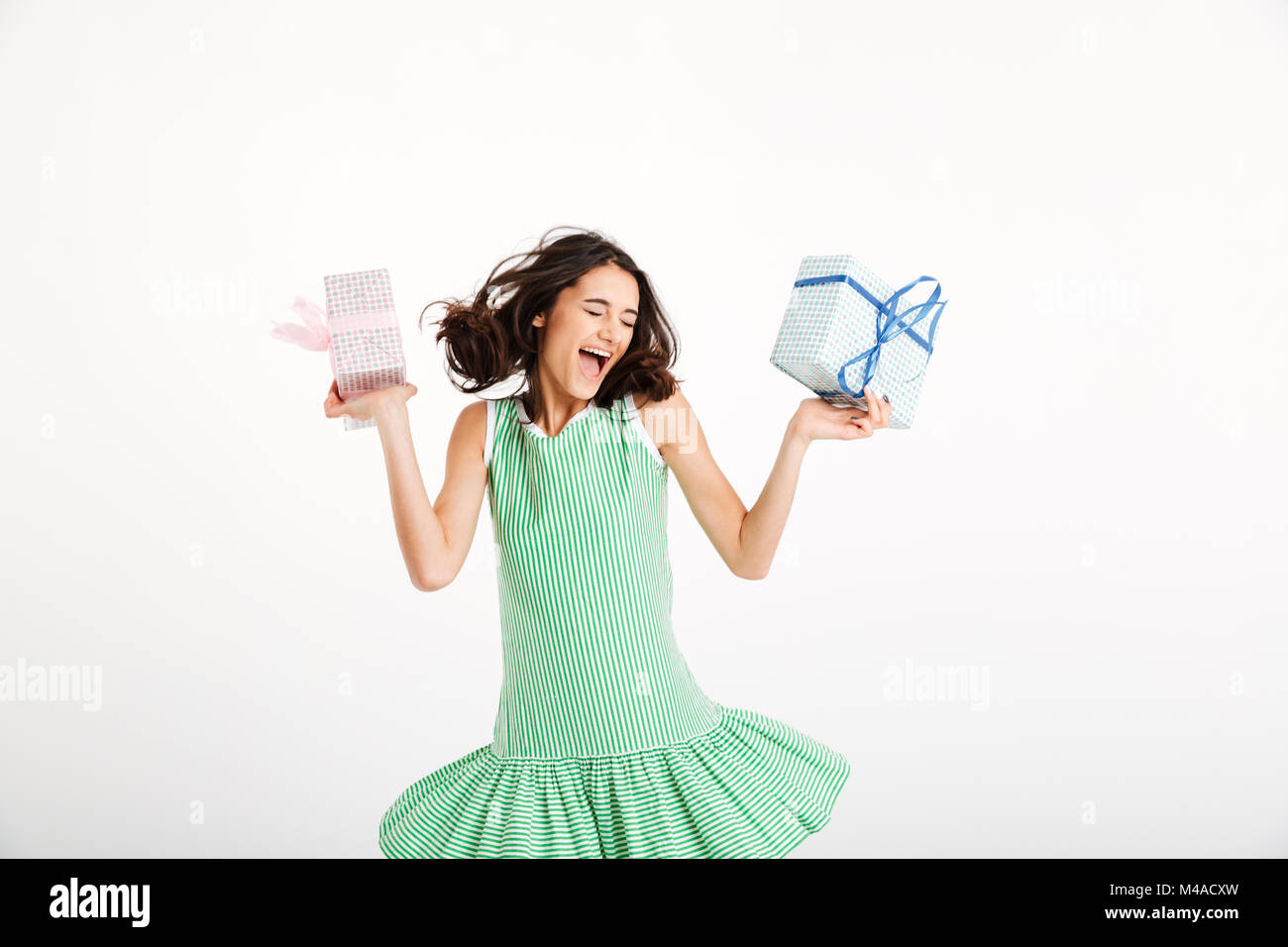 Portrait of a joyful girl dressed in dress holding gift boxes and ...