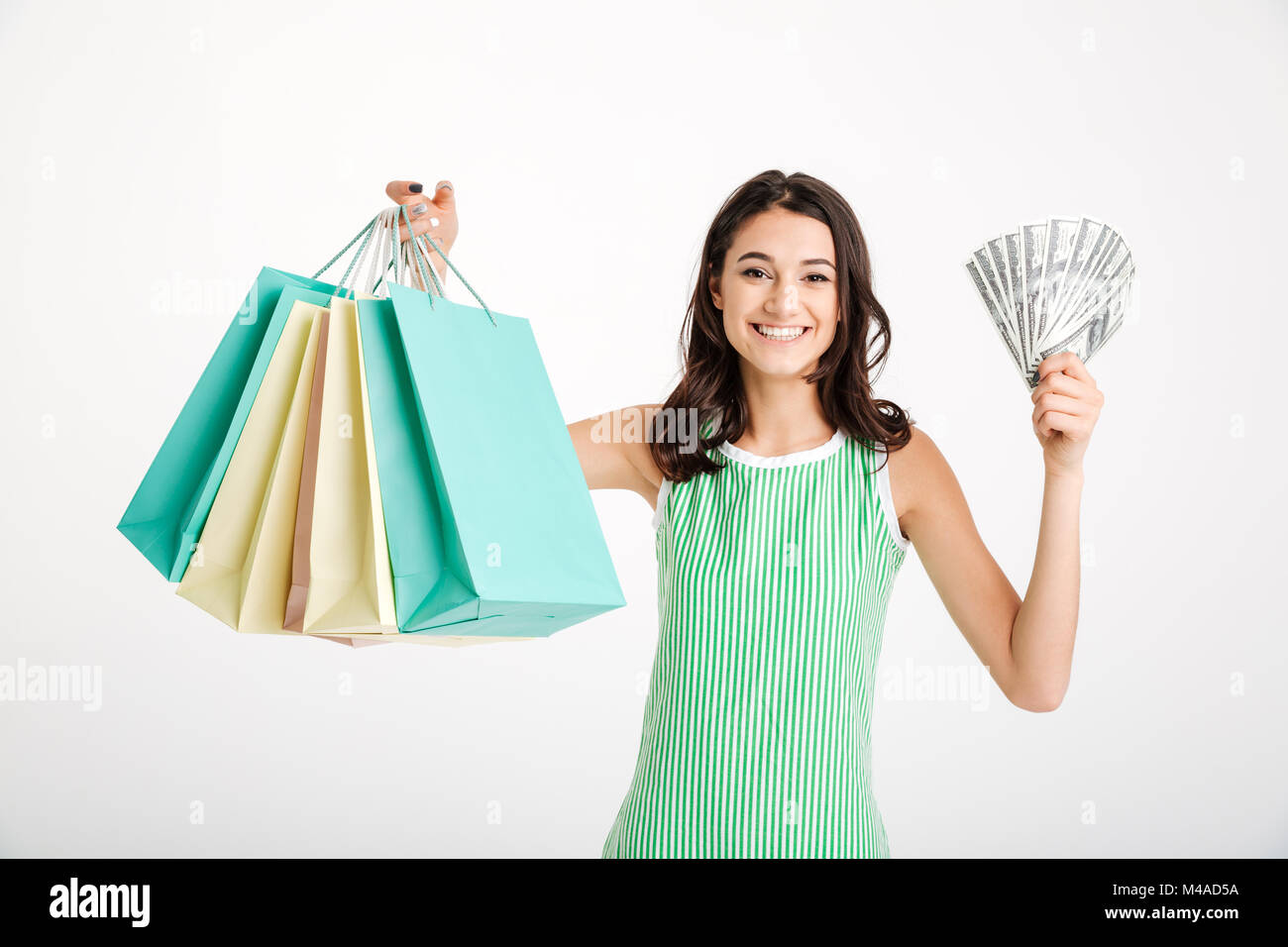 Portrait of a satisfied girl in dress holding shopping bags and showing ...
