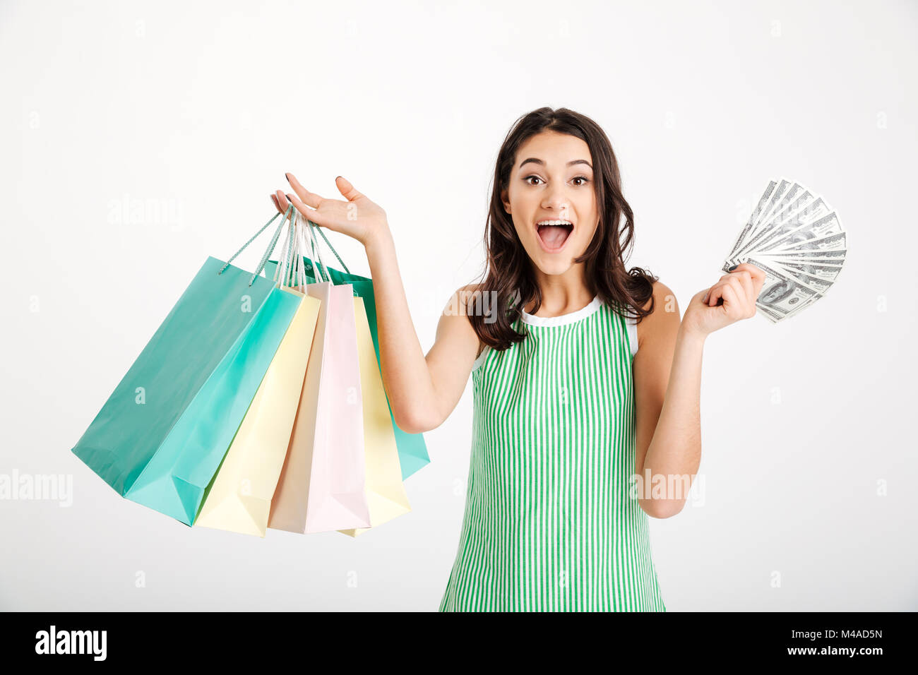 Portrait of a surprised girl in dress holding shopping bags and showing ...