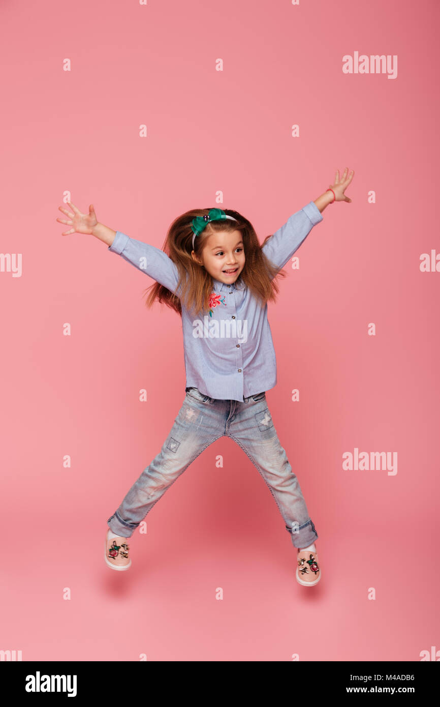 Fulllength picture of joyful carefree child jumping and throwing hands