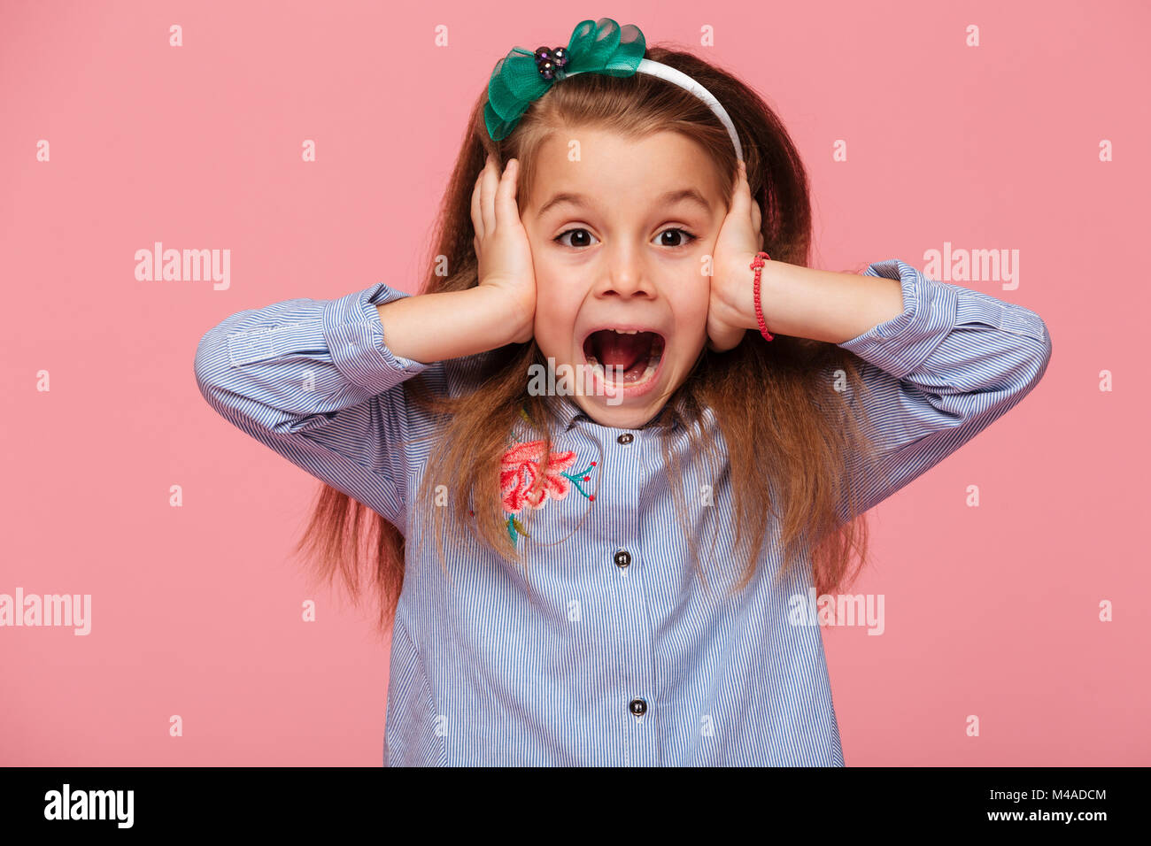 Surprised little girl covering her ears with both hands not listening