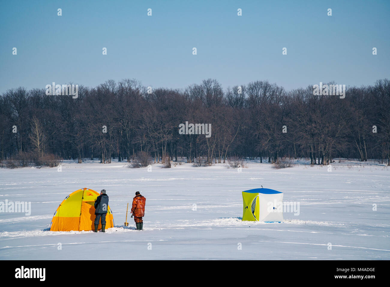 Tents for winter fishing on a frozen lake. Near two fishermen. Winter landscape Stock Photo