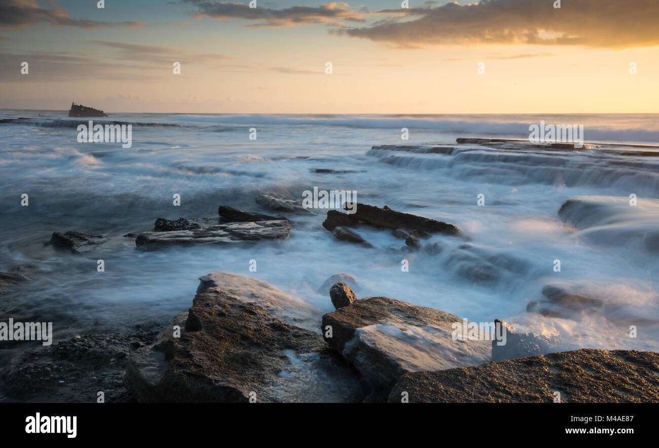 Rocky coast with wavy sea water during sunset at Limassol, Cyprus Stock Photo
