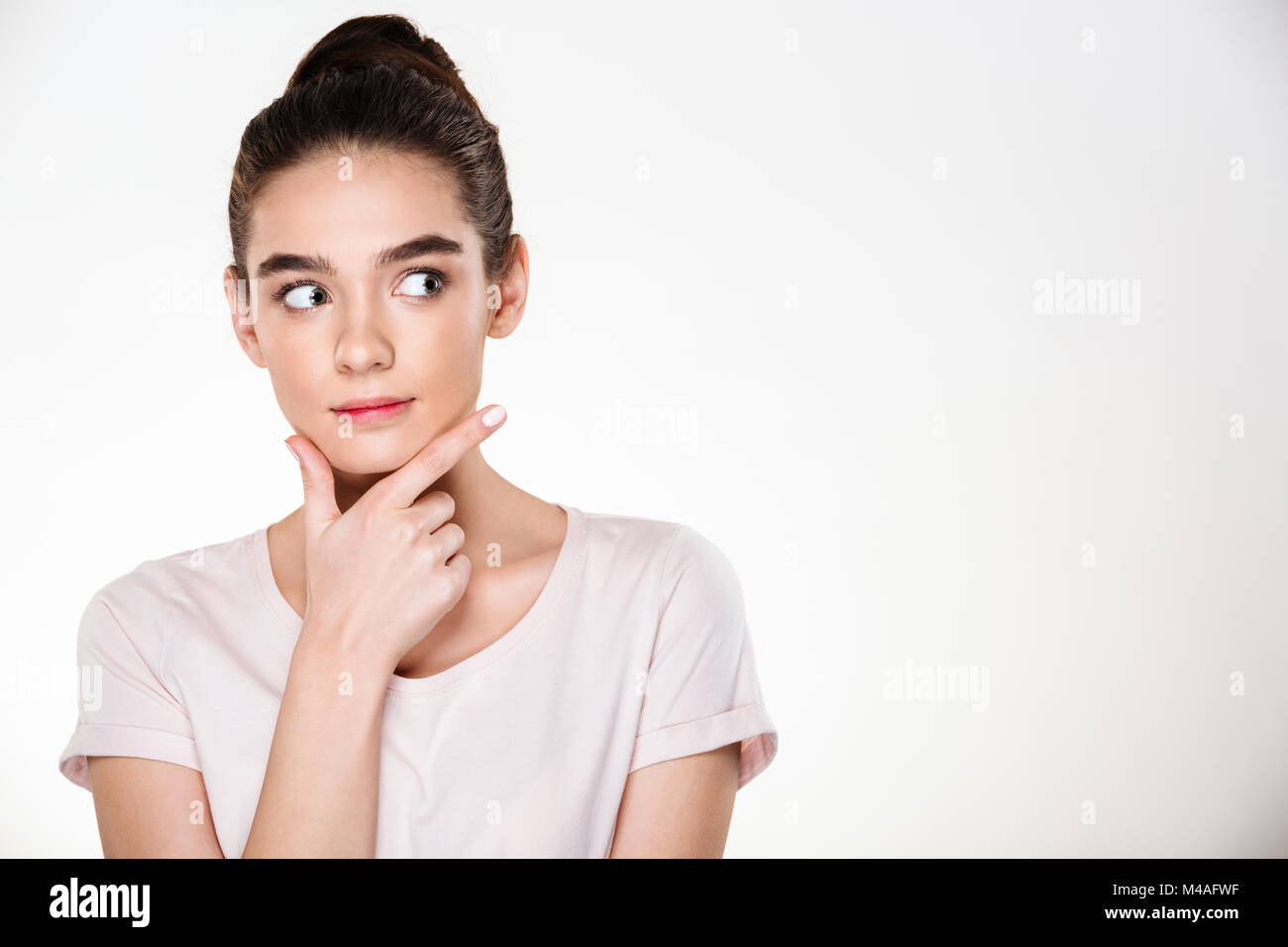 Image of serious woman with brown hair in bun touching her chin while ...