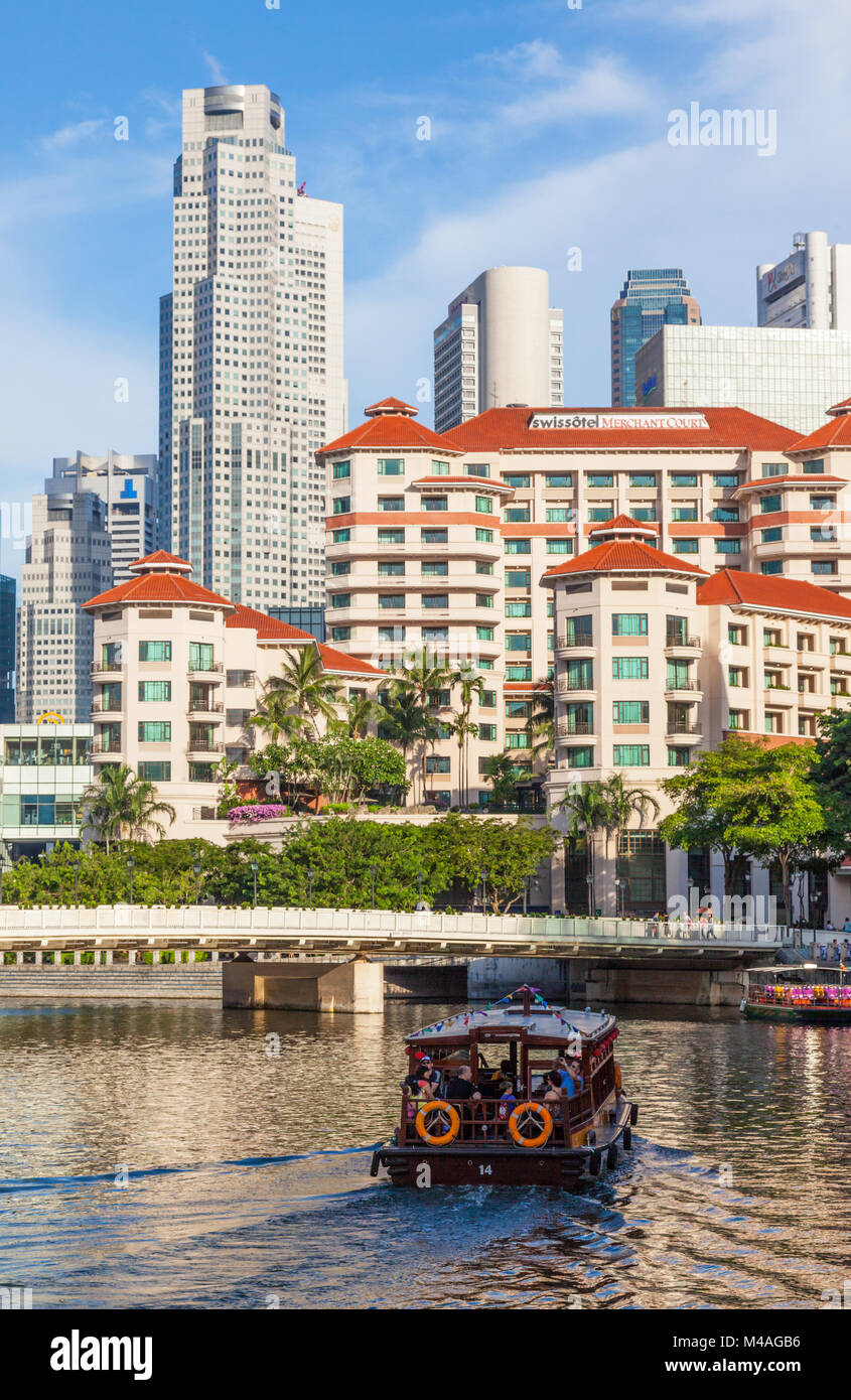 Tourists on a ride in a traditional bumboat on the Singapore River, with the Swissotel Merchant Court Hotel in the background. Stock Photo