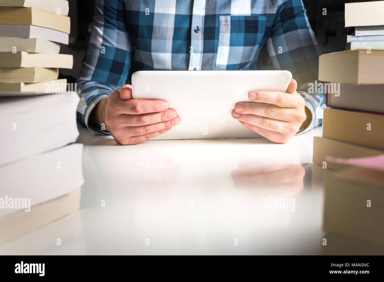 Man holding electronic book reader. Student reading book with tablet and smart mobile device in library or home. Stock Photo