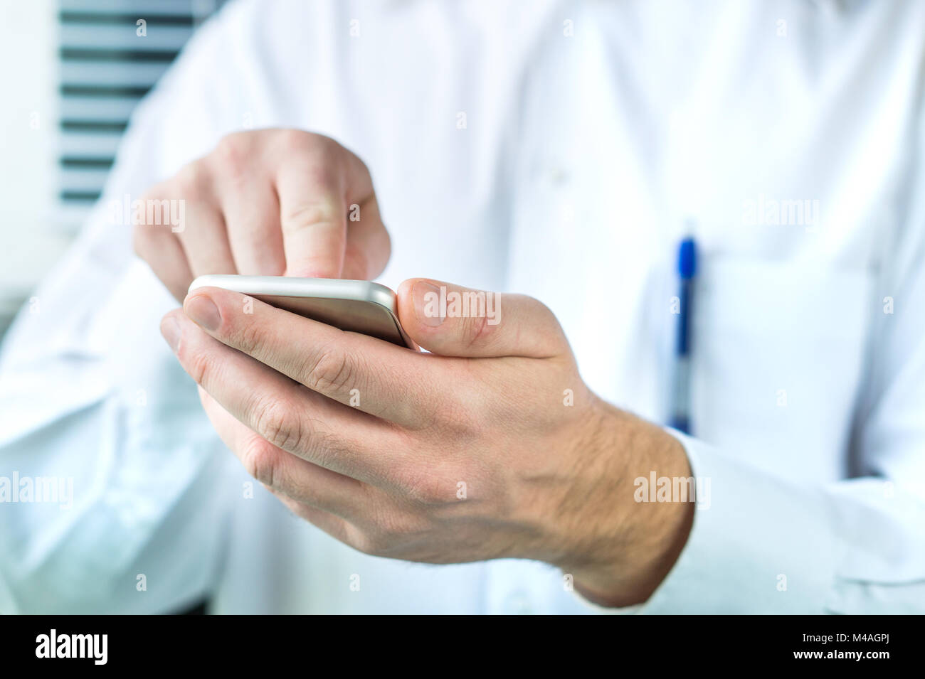 Doctor using mobile phone. Person in white coat typing smartphone. Stock Photo