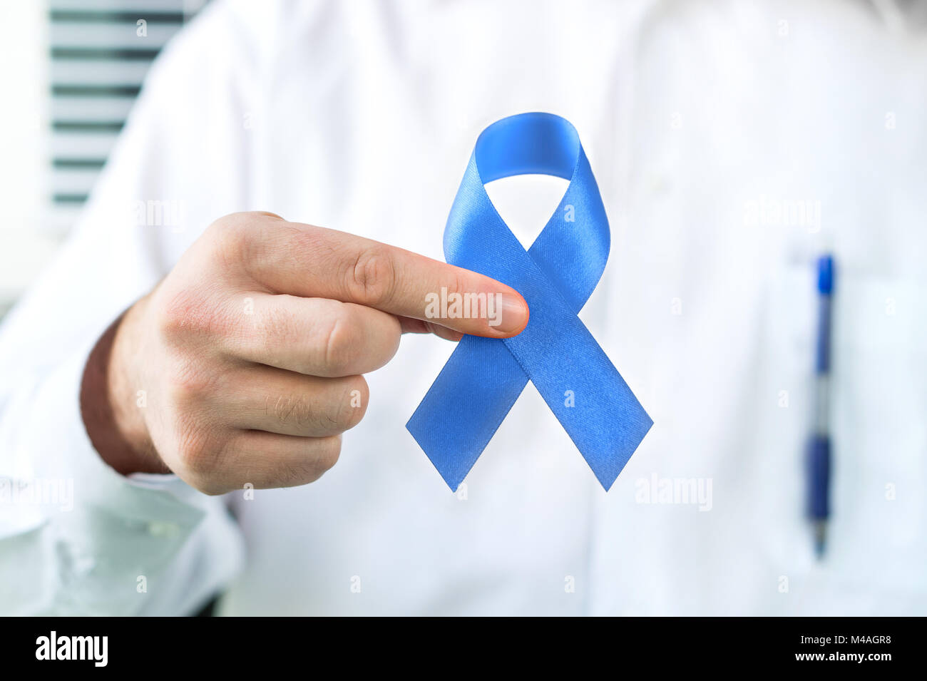 Prostate cancer awareness concept. Doctor holding blue ribbon. Stock Photo