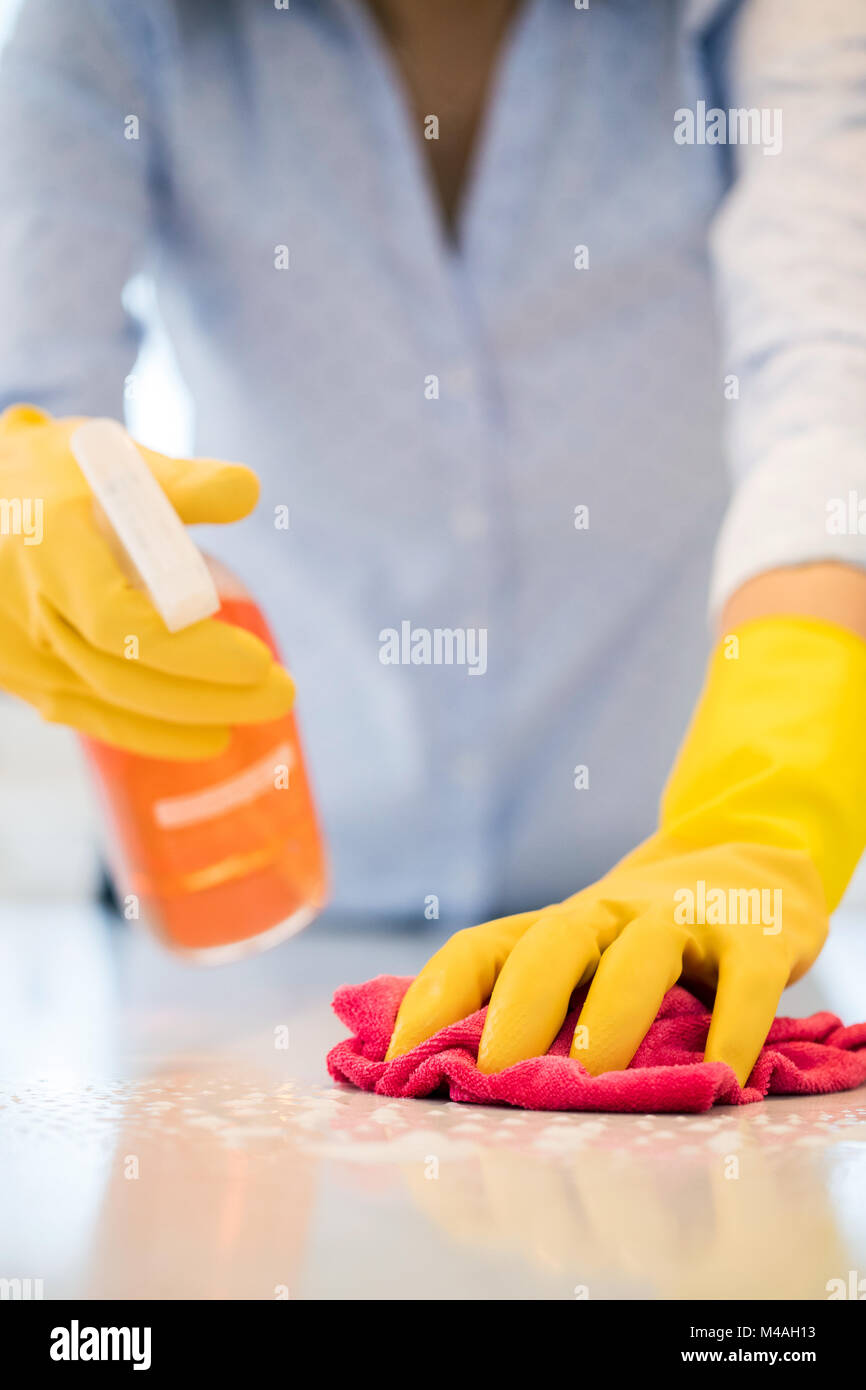 Close Up Of Woman Using Spray Polish To Clean Kitchen Surface Stock Photo