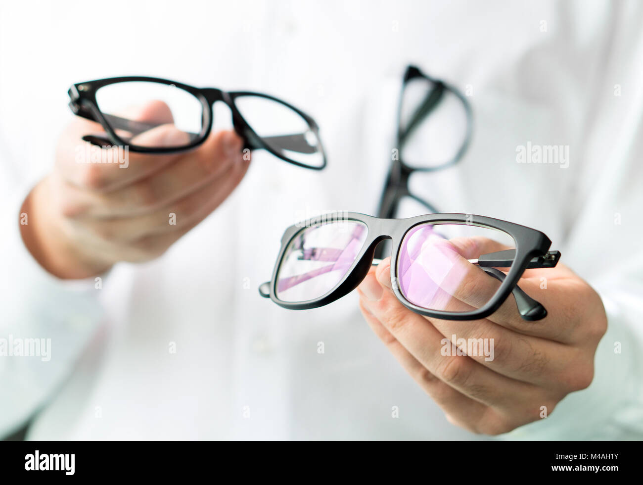 Optician comparing lenses or showing customer different options in spectacles. Eye doctor showing new glasses. Professional optometrist in white coat. Stock Photo