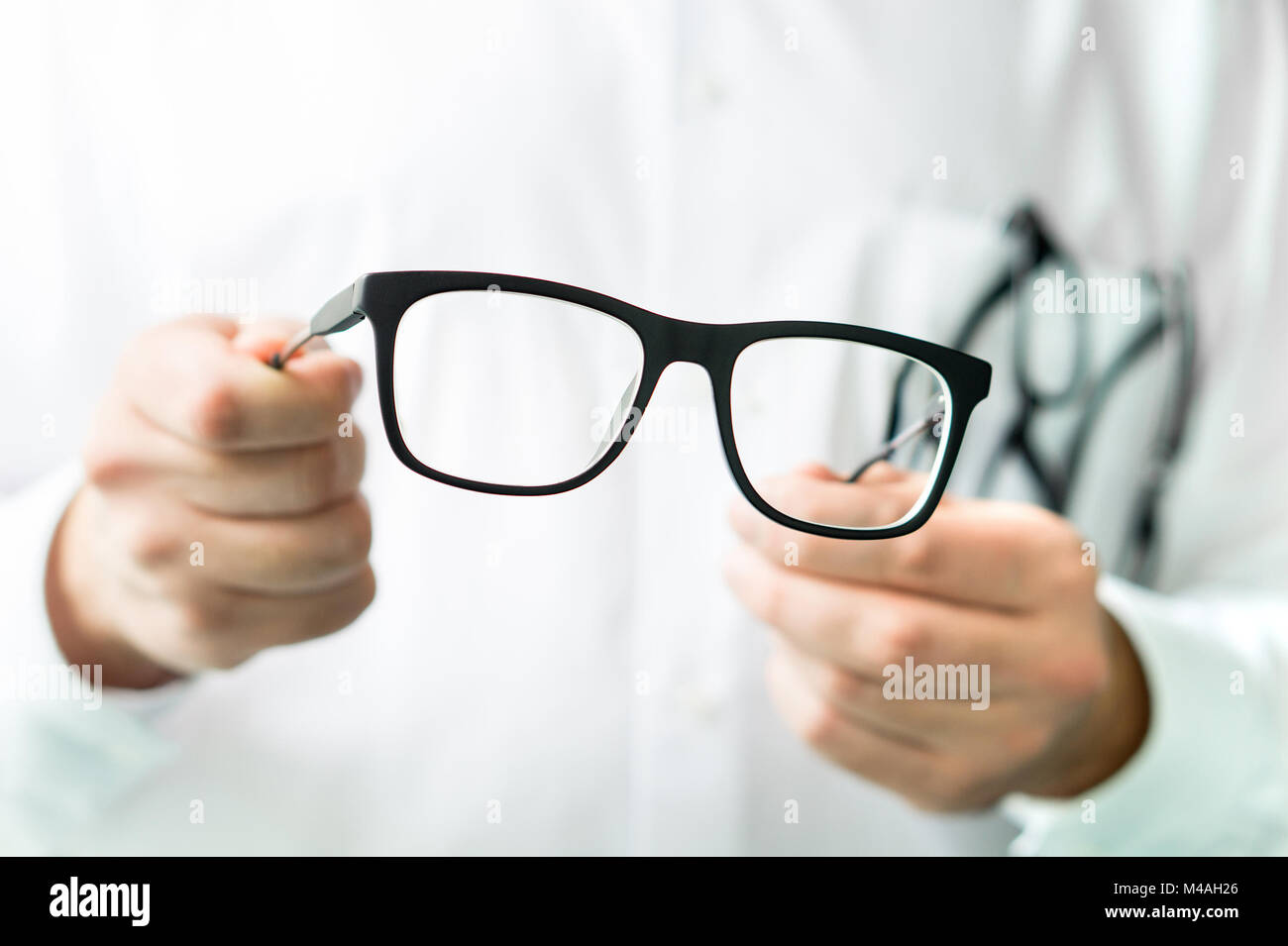 Optician holding glasses. Eye doctor showing new lenses. Professional optometrist in white coat. Stock Photo