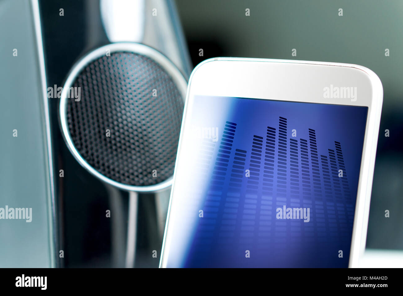 Music streaming with modern portable and wireless smart speaker. Mobile sound application on smartphone screen. Stock Photo