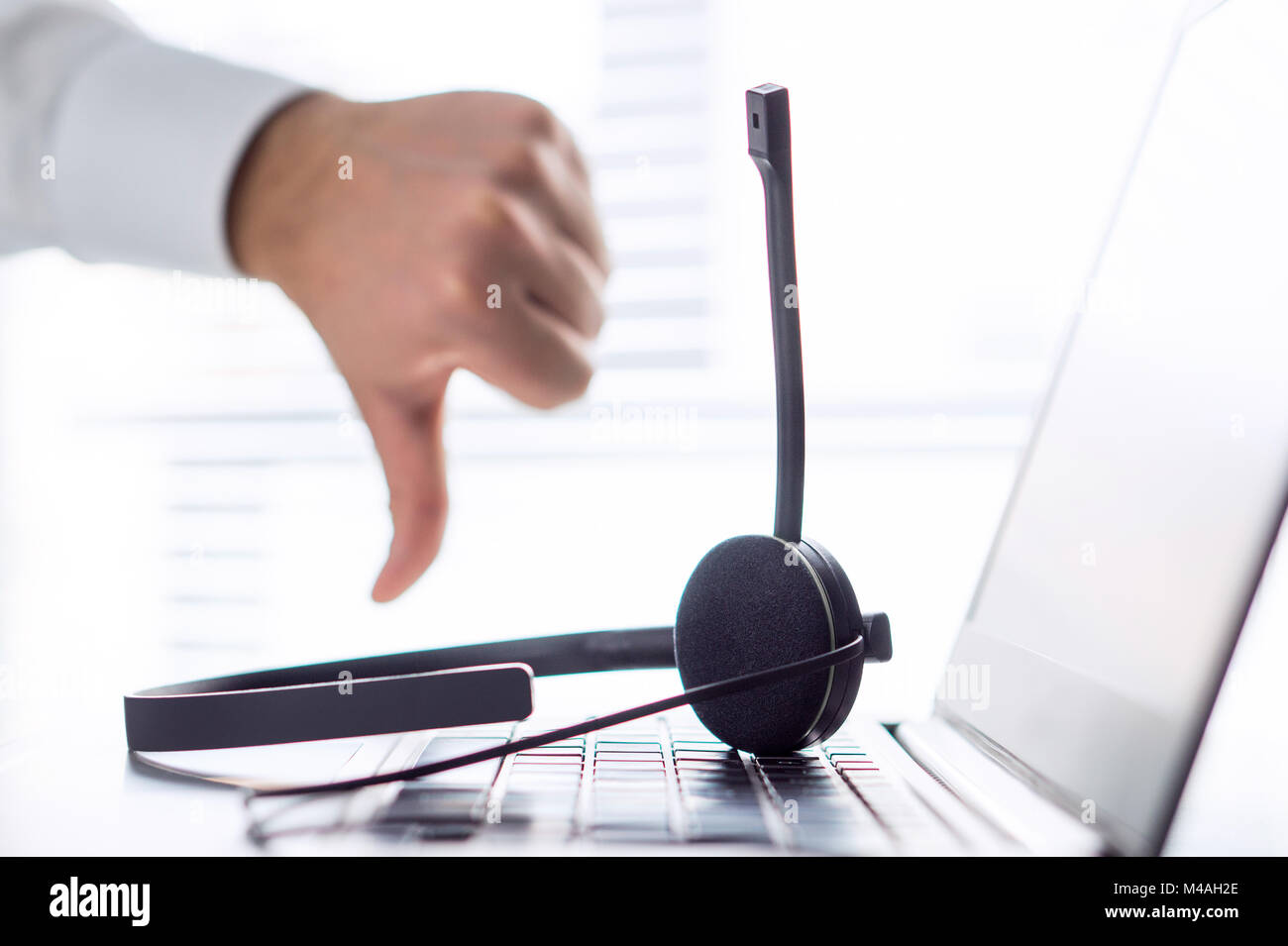 Unhappy help desk, support hotline or call center person showing thumbs down. Tele marketing professional having horrible day, not satisfied. Stock Photo