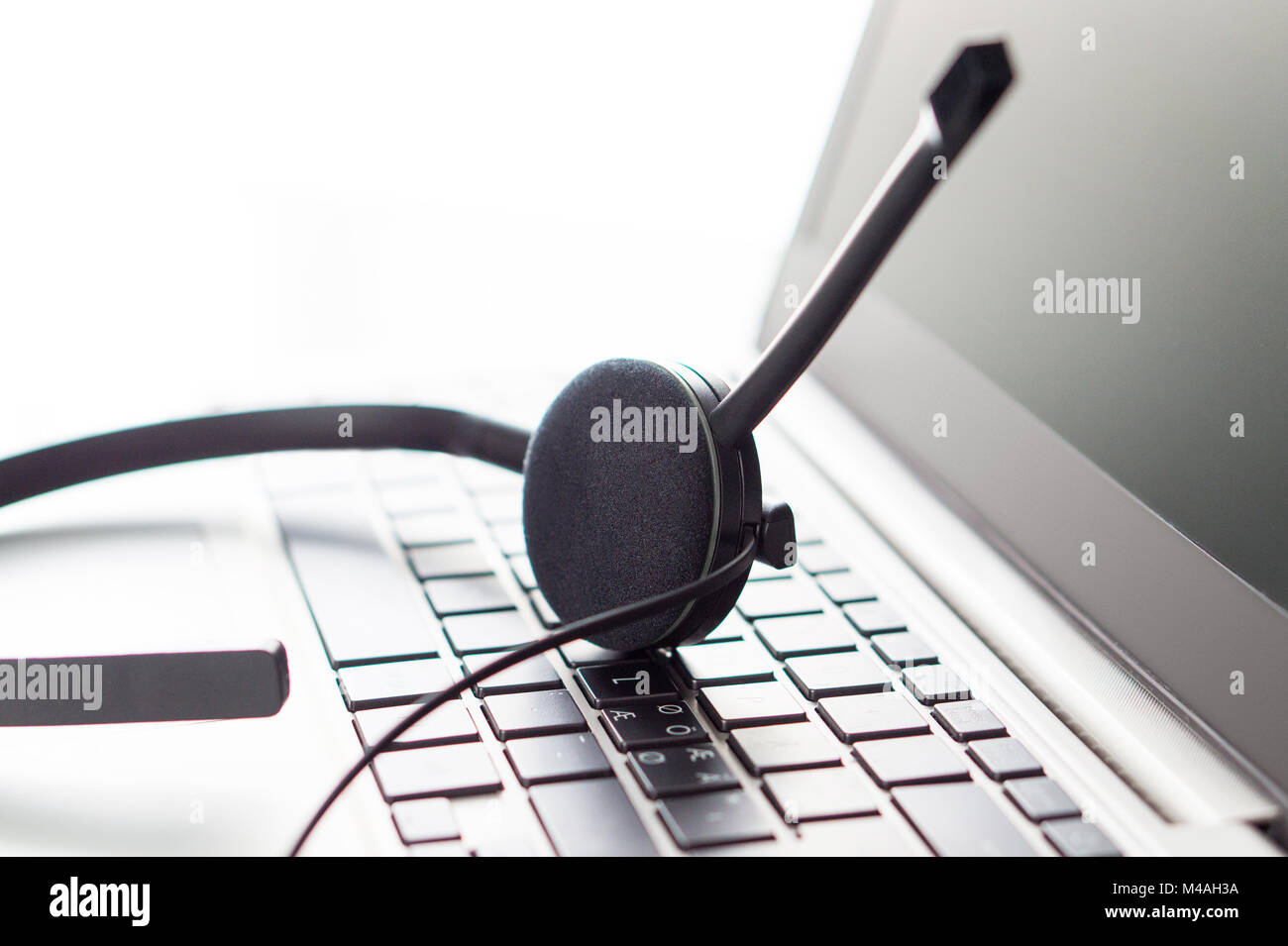 Help desk, customer service, support hotline or call center concept. Close up of headset on laptop keyboard. Video call conference or telemarketing. Stock Photo