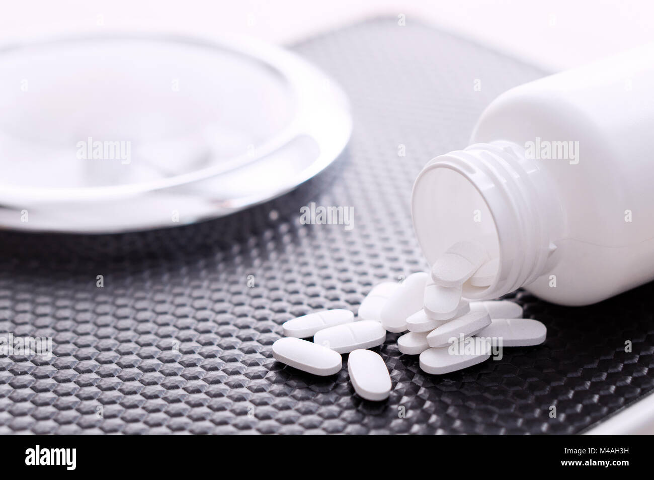 Diet pills on a scale. Weight loss medicine spilled out from bottle. Stock Photo
