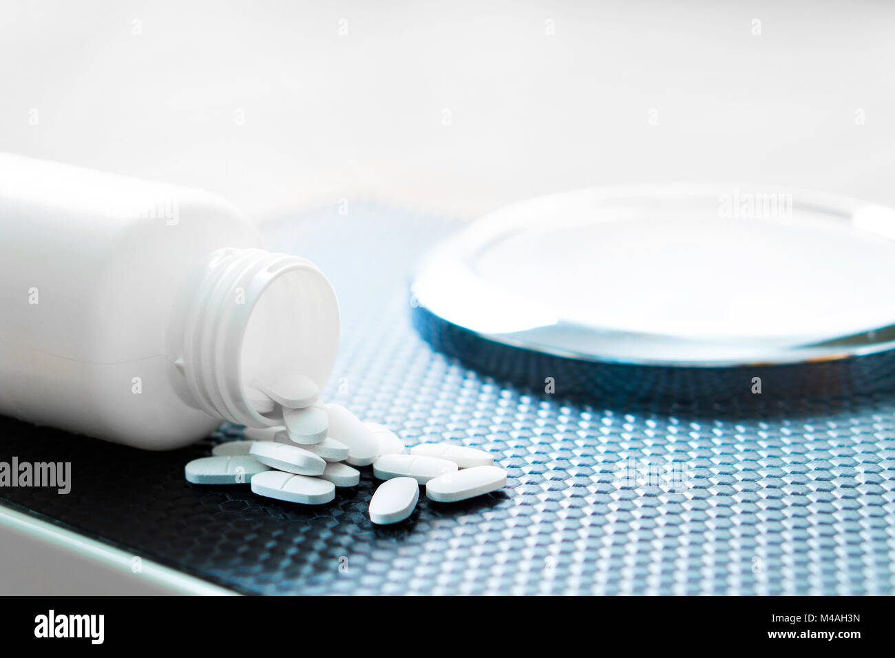 Weight loss pills on a scale. Diet medicine spilled out from bottle. Stock Photo