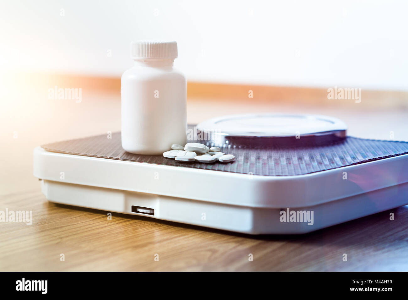 Diet pills on a scale. Weight loss medicine spilled out from bottle. Stock Photo