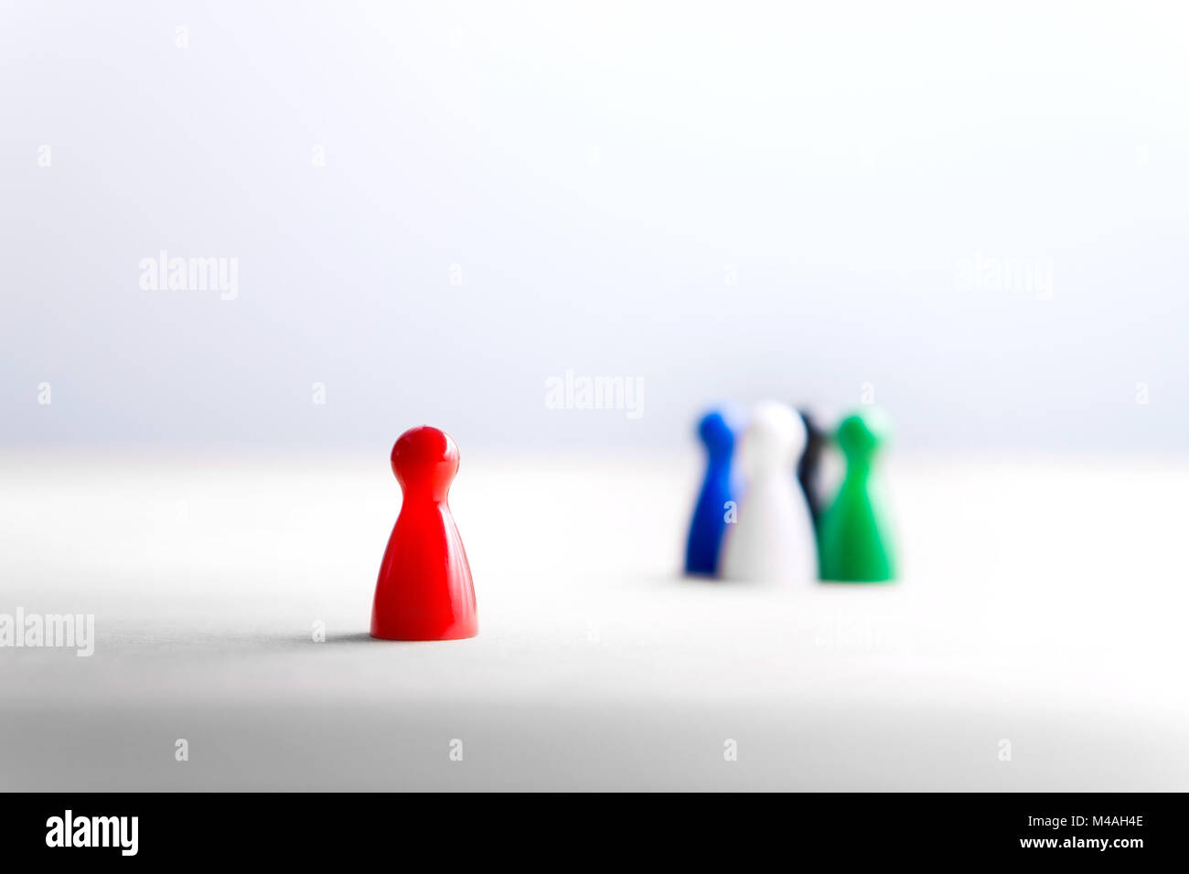 Being alone, outsider and outcast. Racism, discrimination, bullying and social isolation concept. Board game pawns on wooden table. Stock Photo
